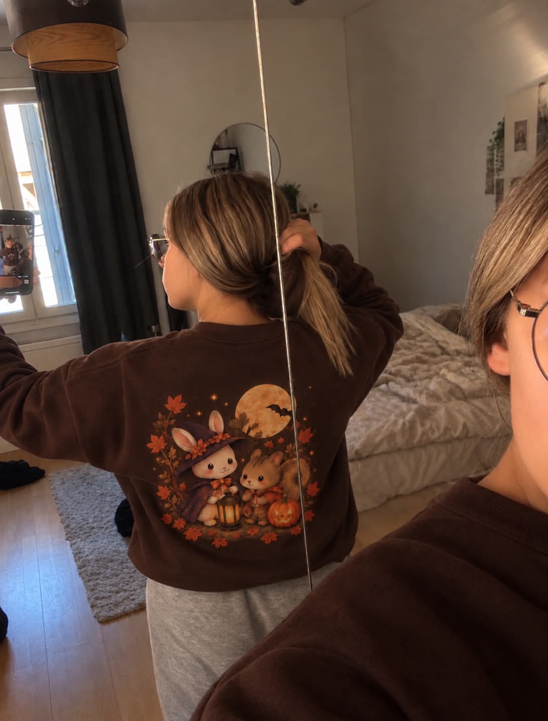 Selfie de dos dans un miroir, sweat chocolat avec la scène d’automne imprimée dans le dos.